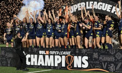 The Tampa Bay Sun raising their arms and celebrating on top of a stage that says USL Super League Champions.