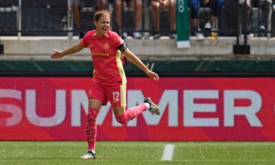 Portland Thorns forward Christine Sinclair celebrates after scoring a goal. She is running with both arms out to her sides like she is flying.