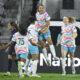 Delphine Cascarino jumps in the air and celebrates a goal with her teammates.