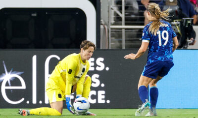 Kyra Carusa approaches Ann-Katrin Berger, who picks up a ball on the ground.