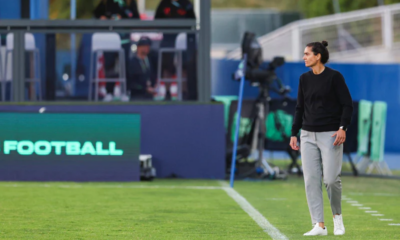 New Boston Legacy FC coach Filipa Patão standing on the pitch during a match and watching the action from the sideline.